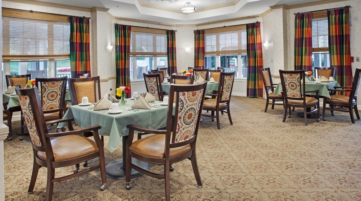 A cozy dining area with elegantly set tables and patterned curtains.