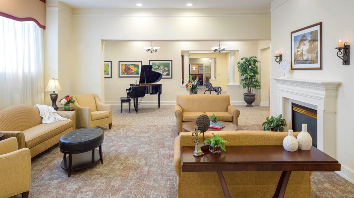 A cozy living room with a sofa, armchairs, and a grand piano.