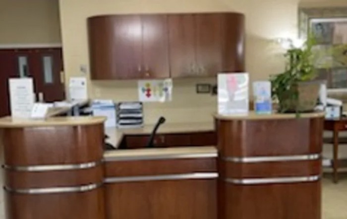 A reception desk in an office setting with wooden furniture and decor.