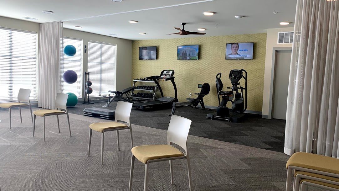 A modern gym with treadmills, stationary bikes, and multiple televisions.