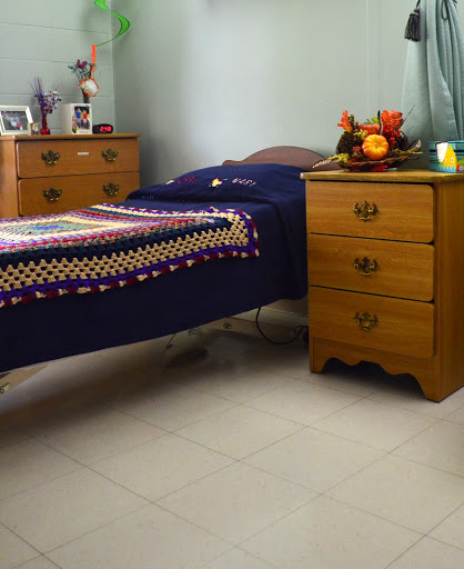 A cozy bedroom featuring a single bed with a colorful blanket and a wooden nightstand adorned with decorative items.