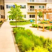A beautifully landscaped garden area outside an apartment building with lush greenery and a walking path.