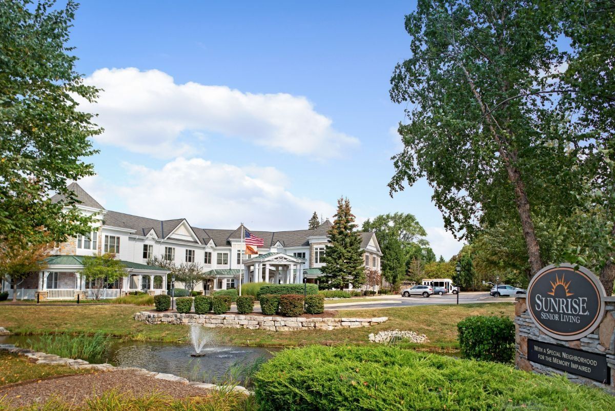 A picturesque view of a hotel with a fountain and lush greenery.