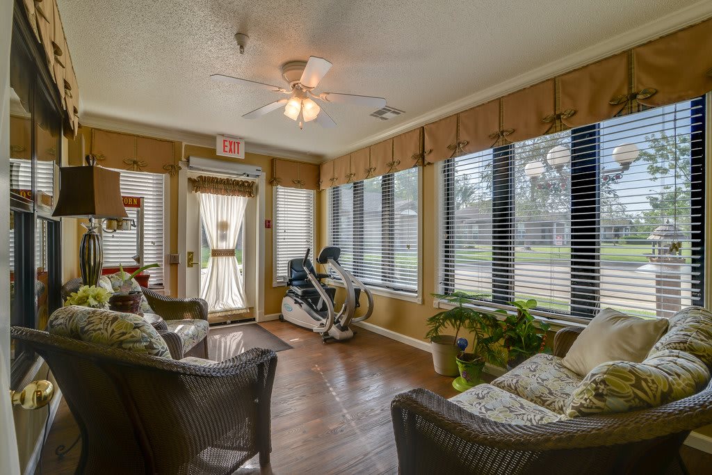 A cozy living room with exercise equipment, large windows, and comfortable seating.