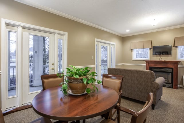A cozy living room area with a wooden table, chairs, and a potted plant.