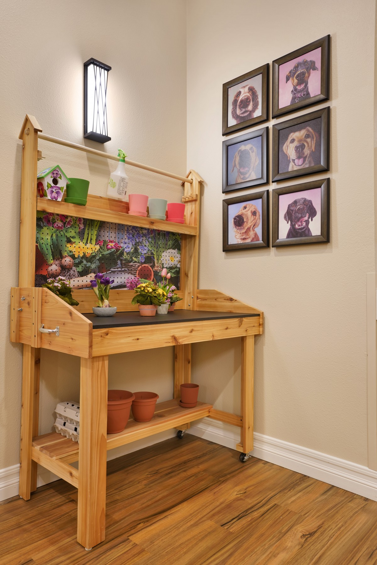 A cozy indoor gardening station with a wooden table, colorful flower pots, and pet-themed wall art.