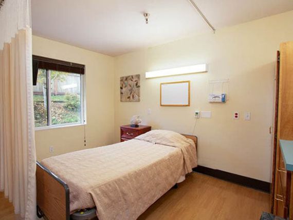 A minimalist hospital room with a single bed and a window providing natural light.