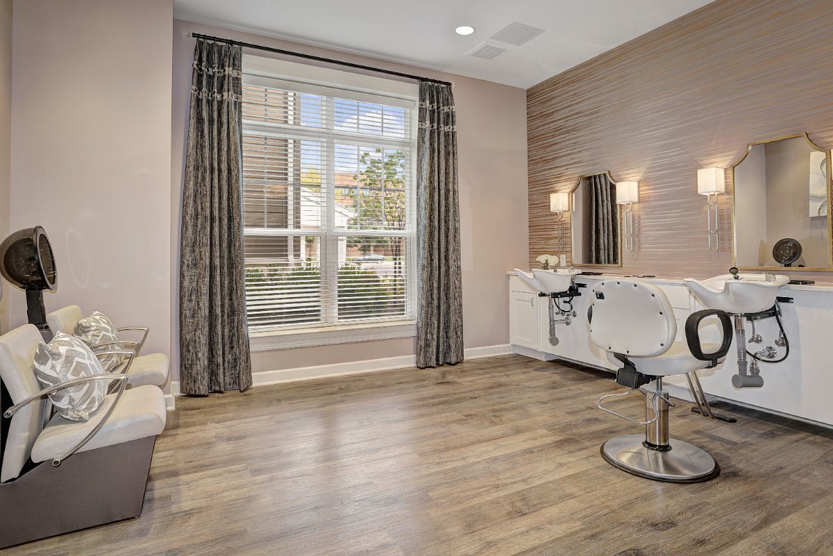 A modern salon interior with a large window, stylish chair, and mirror.