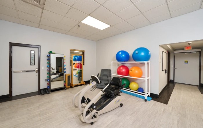 A small gym room with exercise equipment and colorful fitness balls.