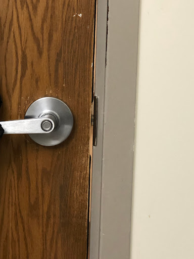 A close-up view of a damaged wooden door with a metal handle.