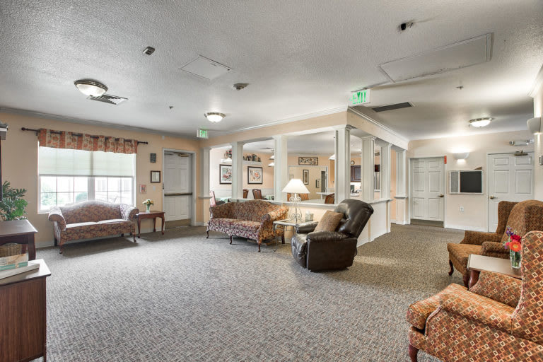 A cozy living room with sofas, chairs, and large windows.