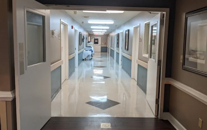 A brightly lit hospital corridor with multiple doors on either side.