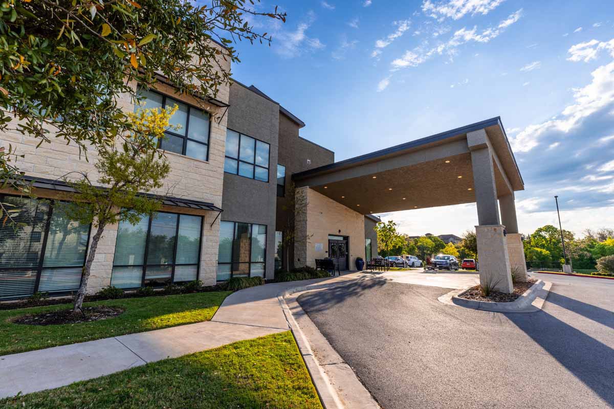 Modern building entrance with a covered driveway and clear blue sky.