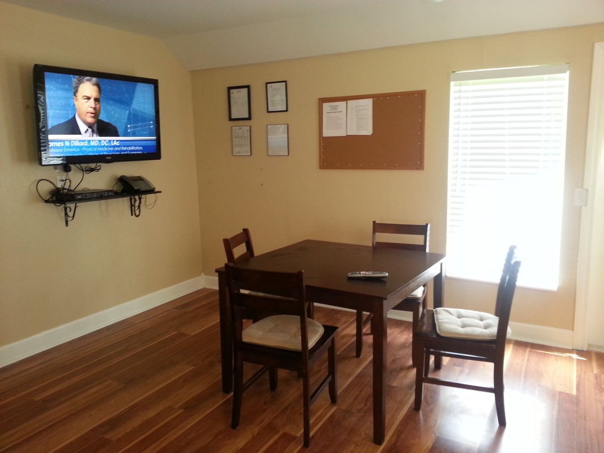 A small office conference room with a table, chairs, and a wall-mounted television.
