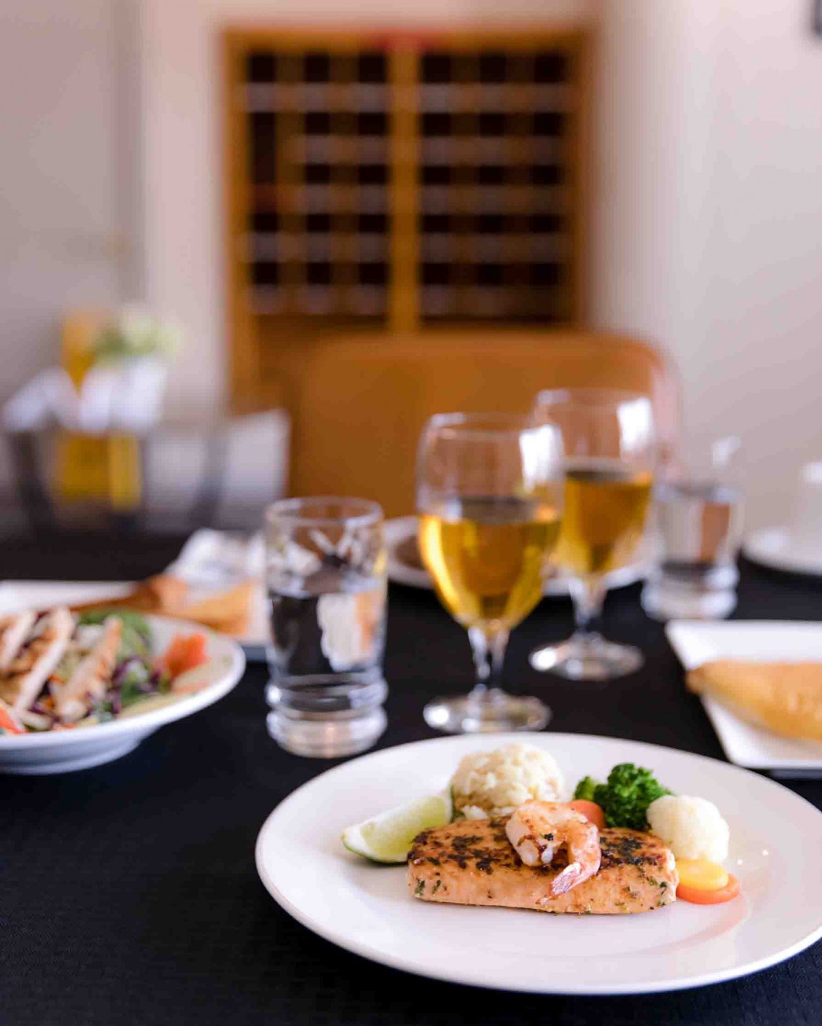 A gourmet meal featuring seafood and white wine served elegantly at a restaurant.