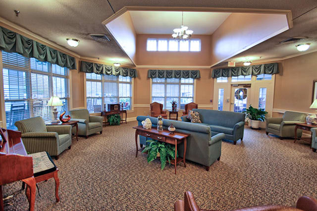 A cozy lobby area with sofas and armchairs arranged around a central table, surrounded by large windows.