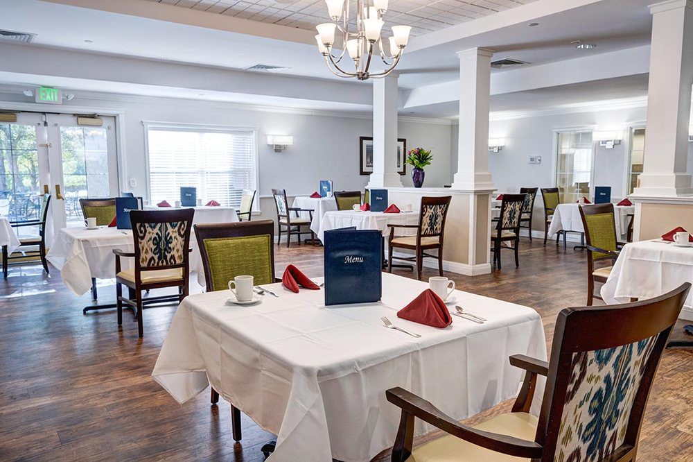 A well-lit dining area with elegantly set tables and comfortable chairs.