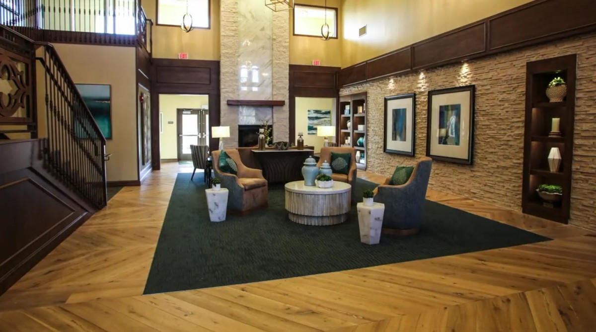 A cozy lobby with modern furniture and a wooden floor, featuring armchairs and a central table.