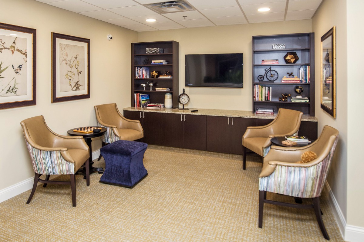 A cozy waiting room featuring comfortable chairs, bookshelves, and a television.