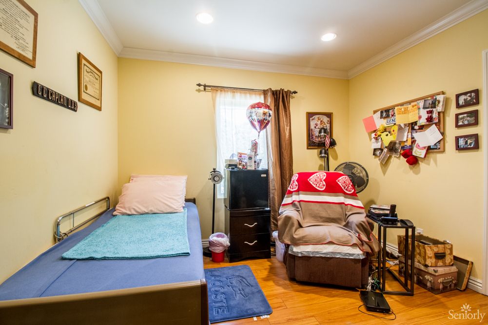 A cozy bedroom with a single bed, armchair, and television.