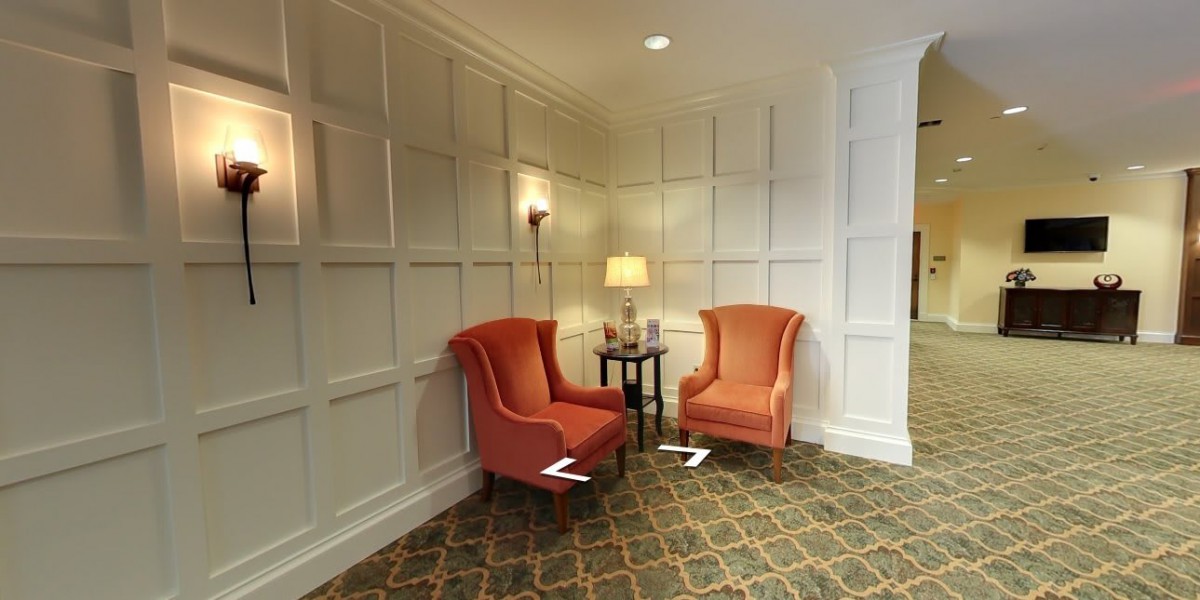 A cozy seating nook with two orange chairs and a small table, illuminated by a lamp.