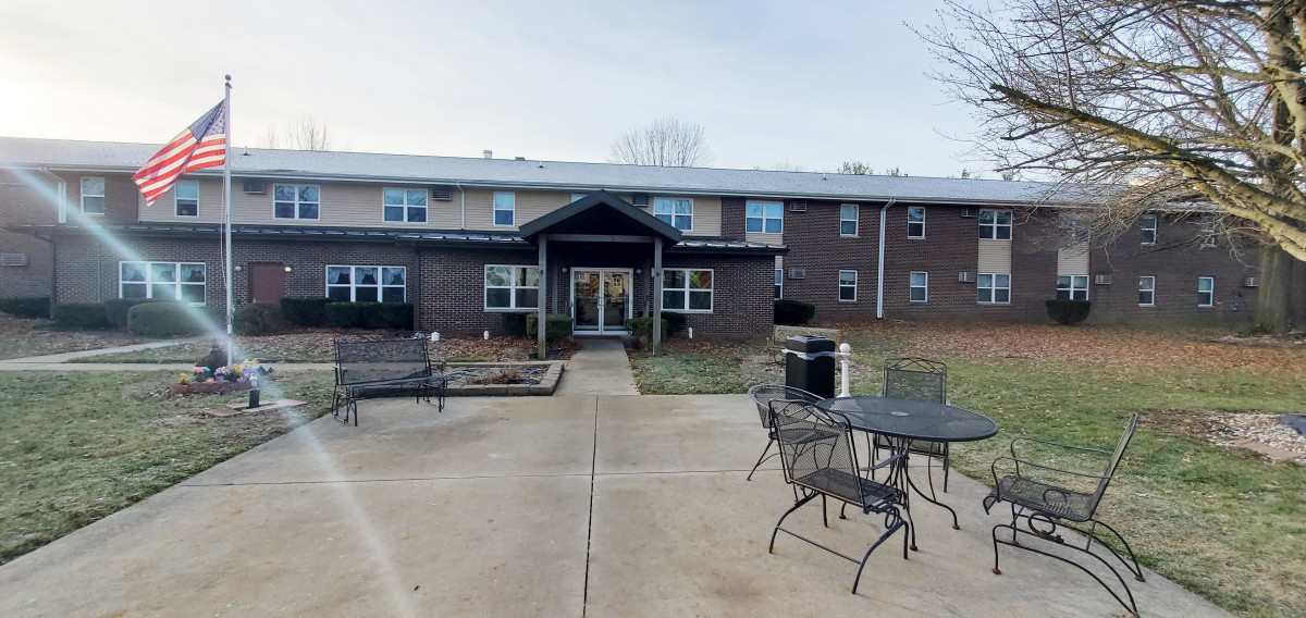 A two-story building with a front entrance and outdoor patio furniture.