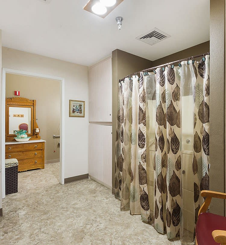 A bathroom with a patterned shower curtain and a vanity area in the background.
