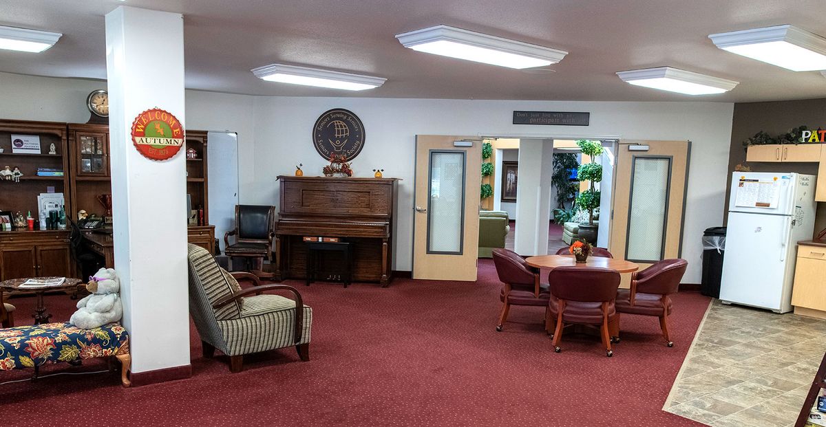 A cozy living room featuring a piano, comfortable chairs, and a round table for gatherings.