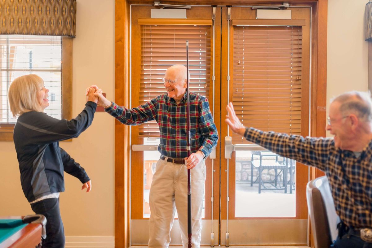 A group of people sharing high fives indoors with smiles on their faces.