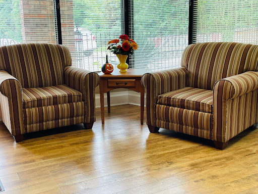 A cozy seating area featuring two striped chairs and a decorative table with flowers.