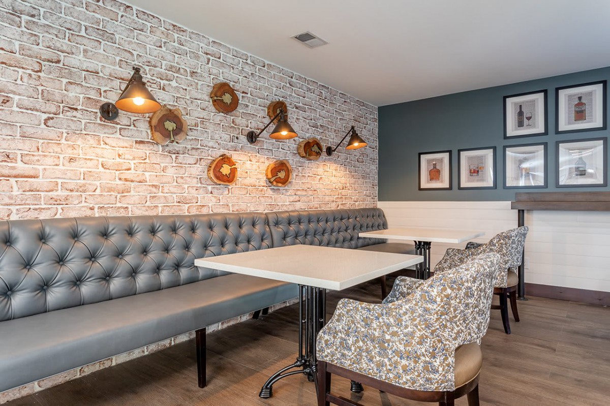A modern restaurant interior featuring a comfortable dining area with stylish lighting and brick wall decor.