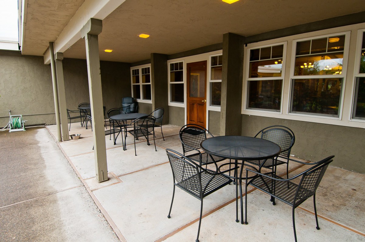 A covered patio area with several tables and chairs arranged for seating.