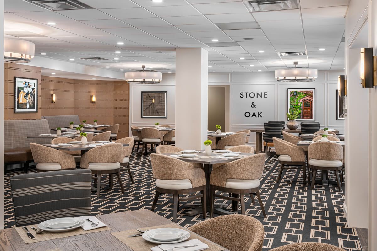 A modern restaurant dining area with neatly arranged tables and chairs, featuring stylish lighting and decor.