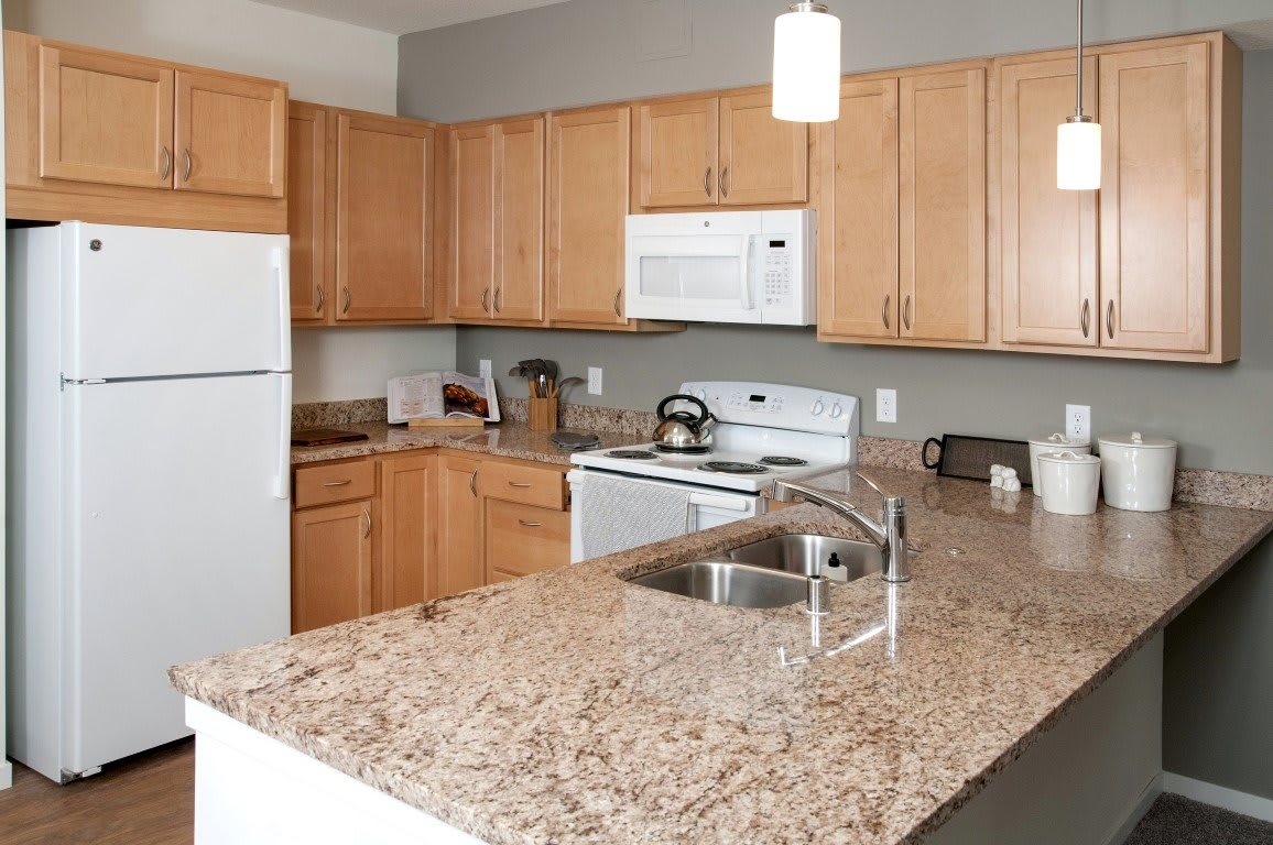 Modern kitchen with wooden cabinets and granite countertops.