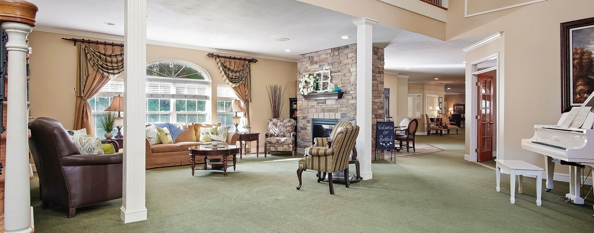 A cozy living room with a fireplace, armchairs, and large windows providing natural light.