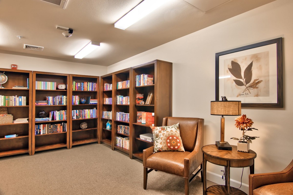 A cozy library corner with bookshelves, a comfortable chair, and soft lighting.