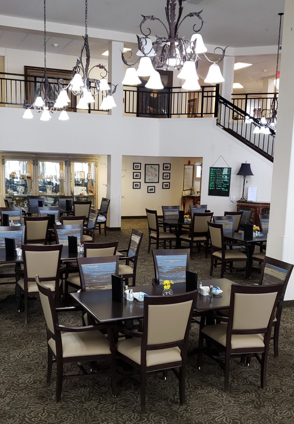 A neatly arranged dining area with tables and chairs, illuminated by hanging lights.