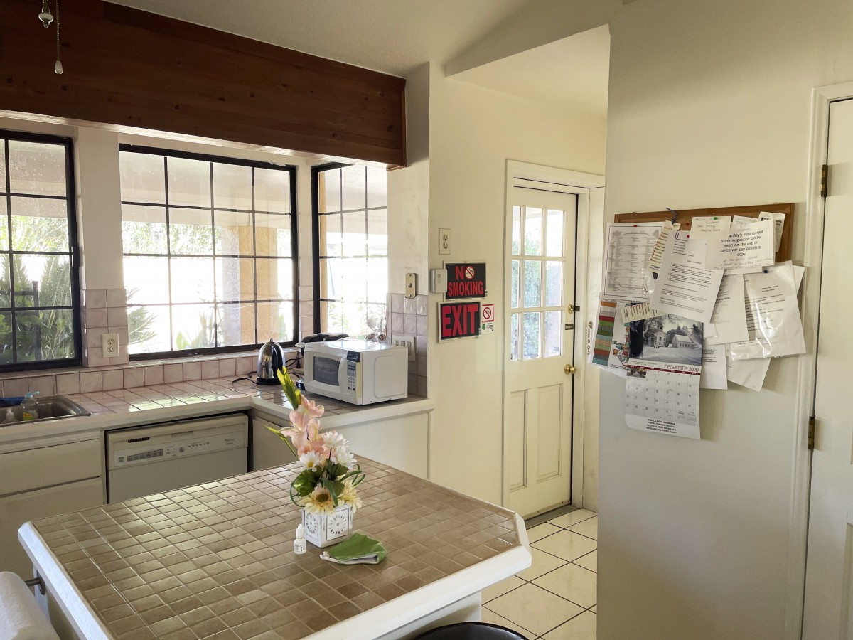 A cozy kitchen featuring a microwave, decorative flowers on the countertop, and large windows letting in natural light.