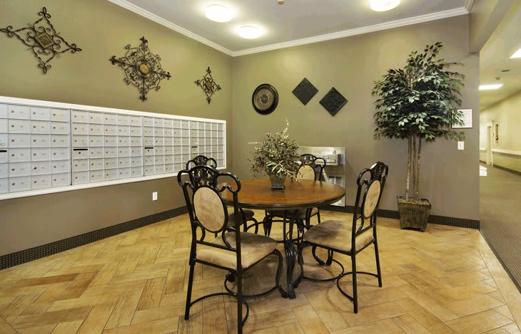 A cozy interior space with a round table and four chairs, adorned with decorative wall art and a potted plant.