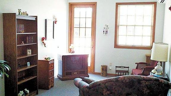 A cozy living room with a sofa, television, and large window allowing natural light.