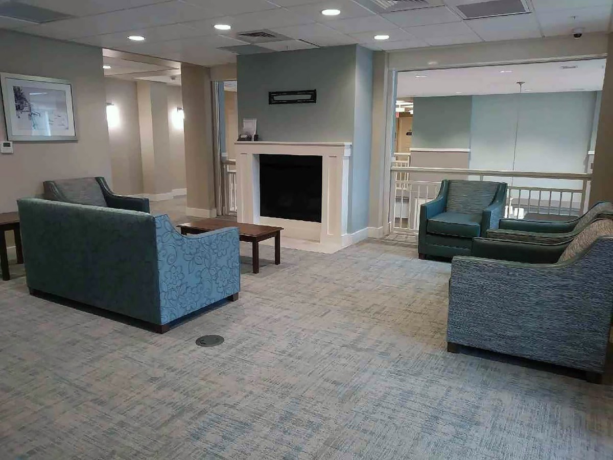 A modern living room with blue sofas, a fireplace, and carpeted flooring creating a cozy atmosphere.