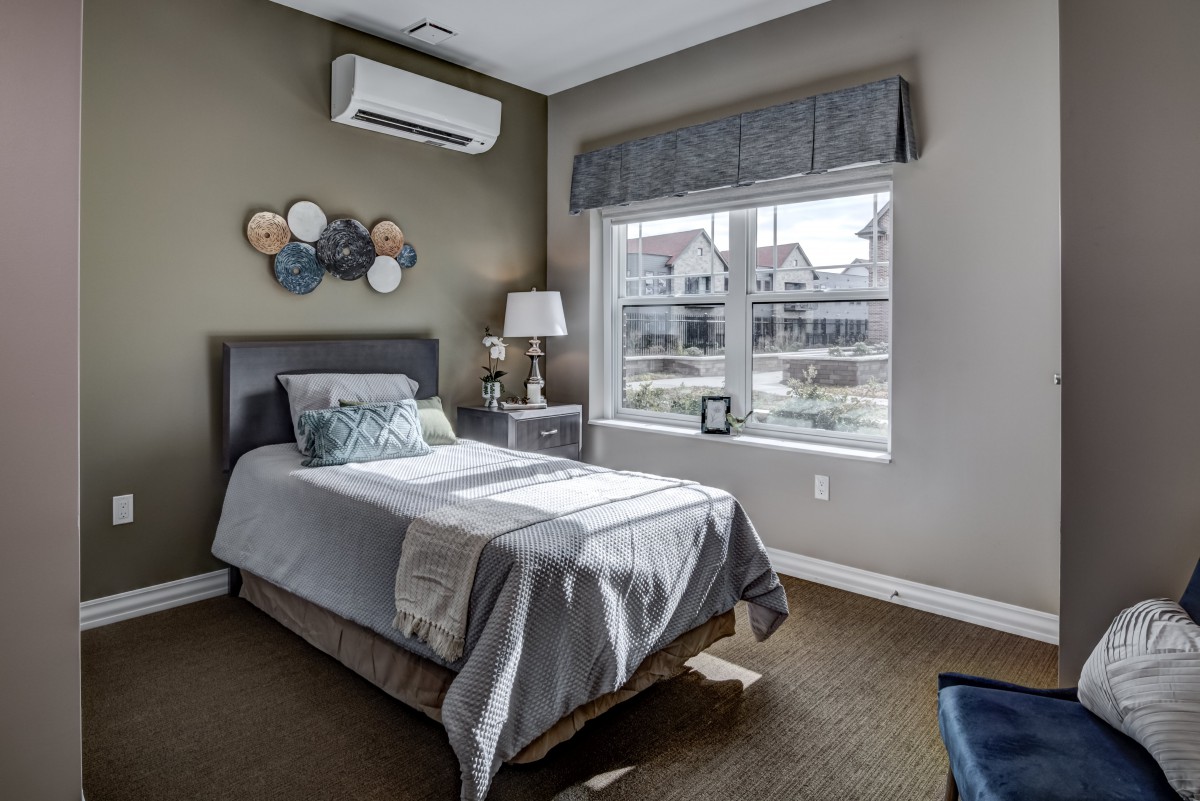 A cozy bedroom with a single bed, featuring neutral tones and equipped with an air conditioner.