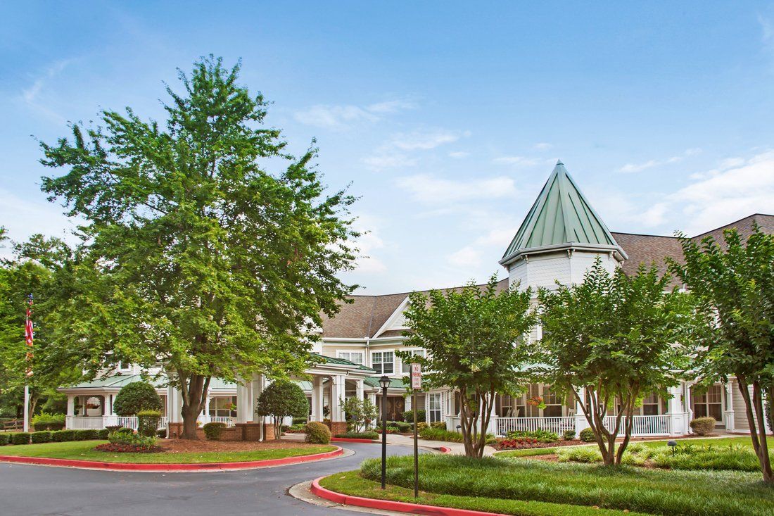A picturesque residential building with a distinctive turret and surrounding trees.