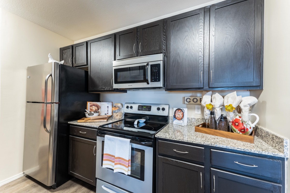 A modern kitchen with dark cabinets and stainless steel appliances.