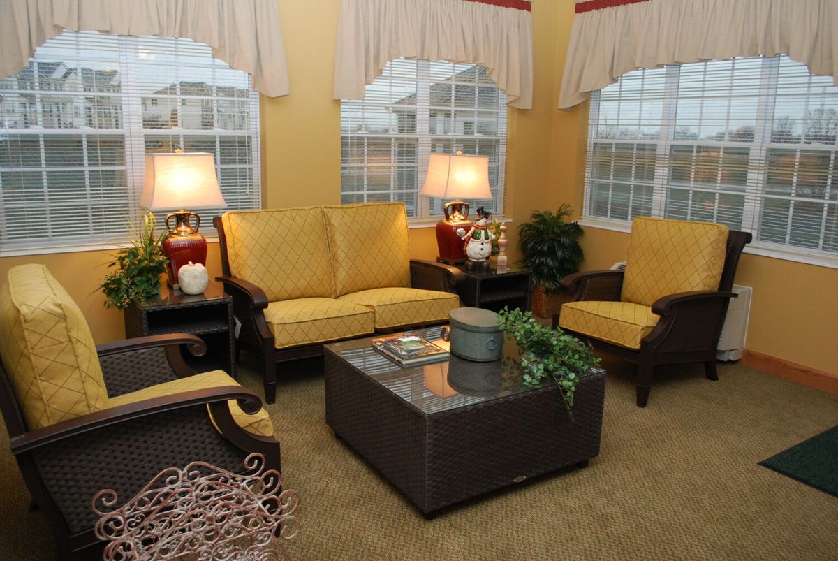 A cozy living room with yellow sofas, armchairs, a coffee table, and warm lighting from lamps.