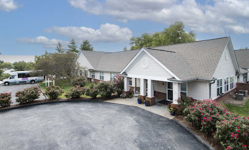 A view of a well-maintained residential building with landscaped gardens and a driveway.