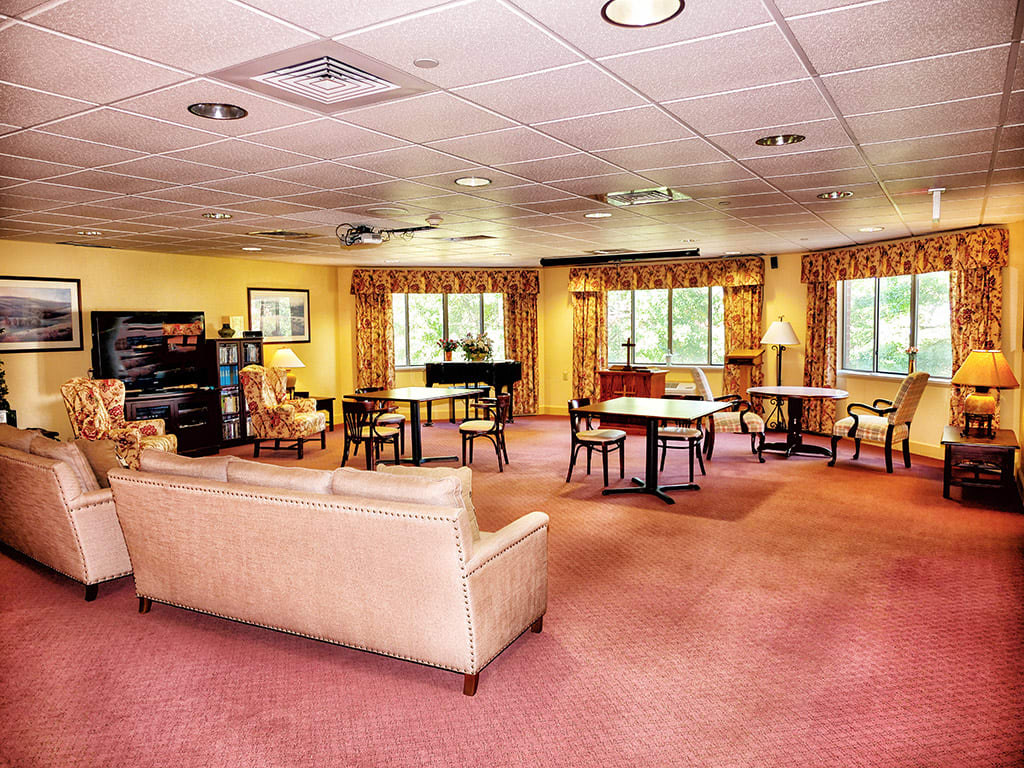 A spacious living room with comfortable seating, a piano, and large windows.