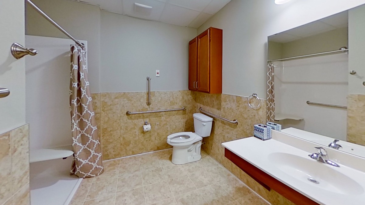 An accessible bathroom with a toilet, sink, and safety grab bars.
