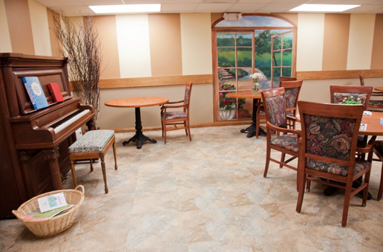 A cozy room with a piano and seating area, featuring a decorative window mural.