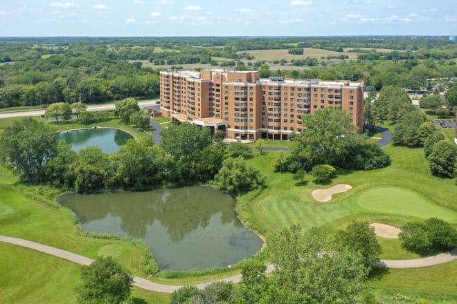 Aerial view of a residential building surrounded by a golf course and ponds.